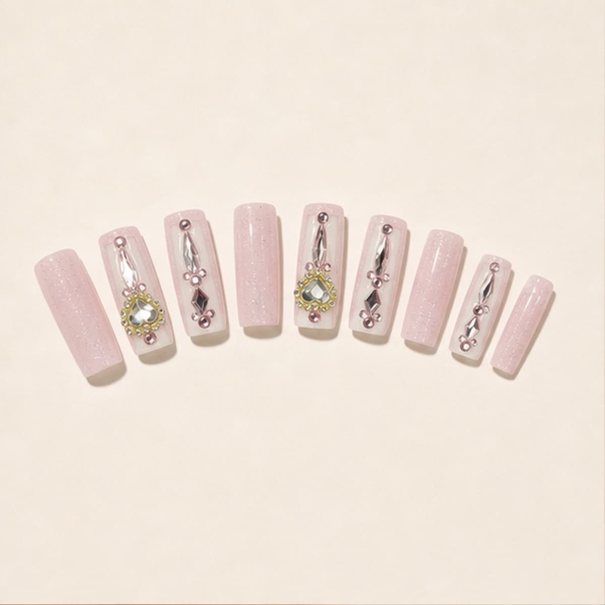 Amour crystal heart sculpture press-on nail set arranged in a fan on an ivory background