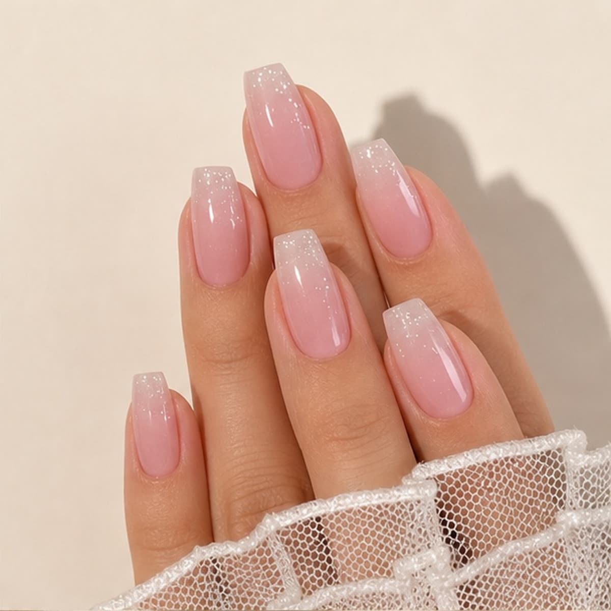 Nacre blush shimmer press-on nails worn on a relaxed hand against a cream background
