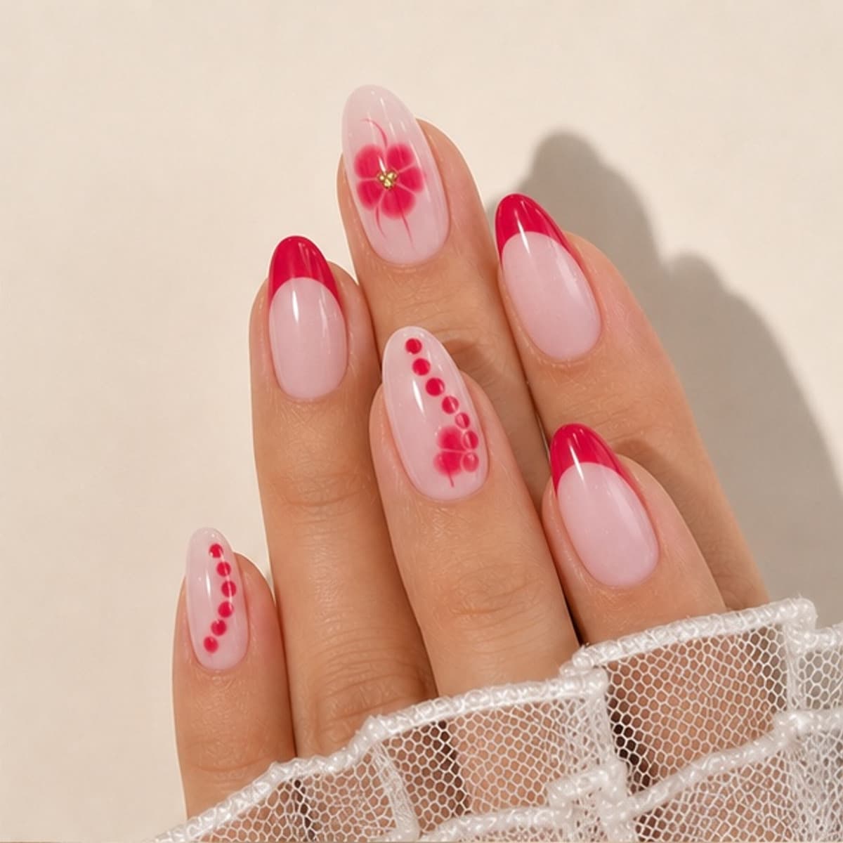 Rubis ruby floral French press-on nails worn on a relaxed hand against a cream background