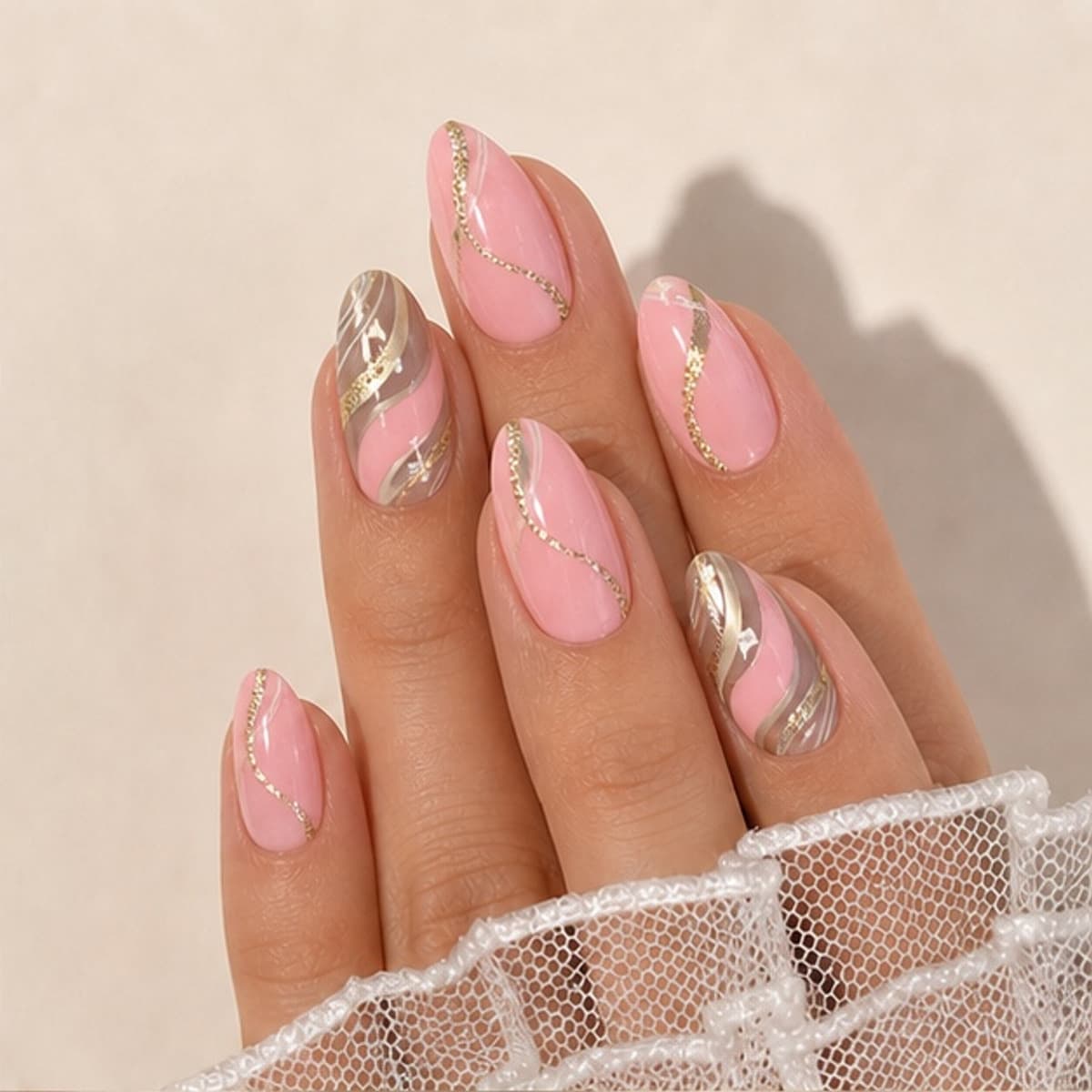 Velours pink and champagne ripple press-on nails worn on a relaxed hand against a cream background